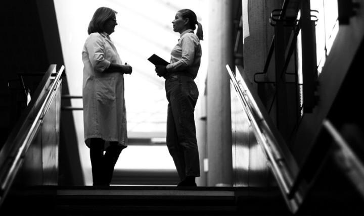 To ansatte i en skole står på toppen av en trapp og prater sammen.