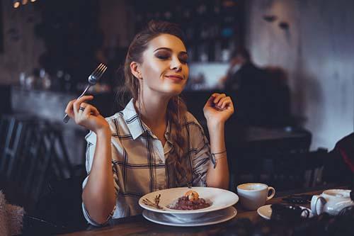 Restaurantgjest lukker øynene og nyter et godt måltid i trygge, hygieniske omgivelser.